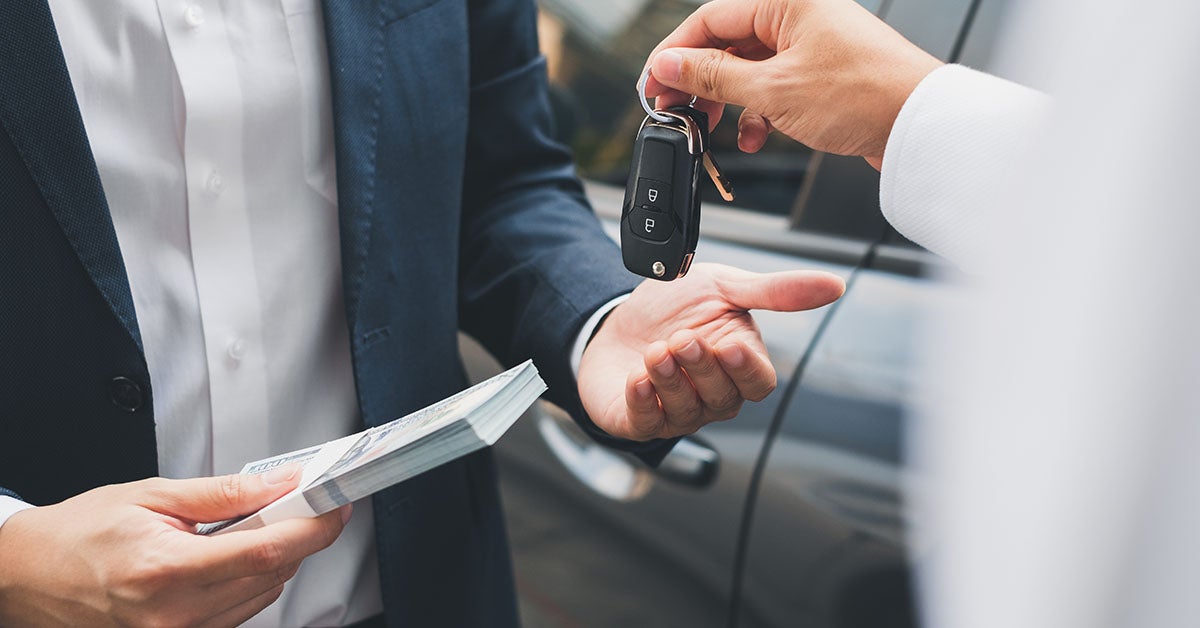 Cash and keys exchanging hands as part of Nissan trade-in